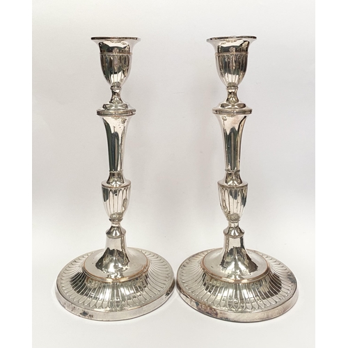 67 - A PAIR OF DECORATIVE GEORGE V STYLE SILVER PLATED CANDLESTICKS, with fluting to urn shaped sockets, ... 