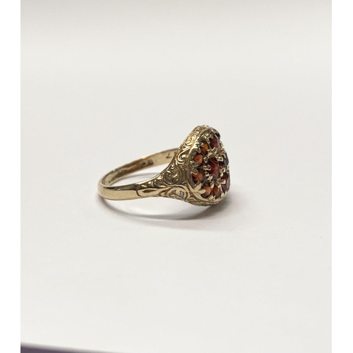 73 - A VINTAGE 9CT YELLOW GOLD GARNET CLUSTER RING, with fifteen round cut garnets of varying sizes claw ... 