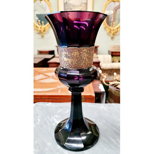 76 - AN ART DECO EARLY 20TH CENTURY MOSER KARLSBAD STYLE AMETHYST GLASS WITH OROPLASTIC GILT BAND DEPICTI... 