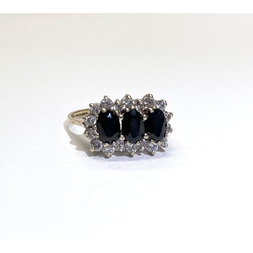 80 - A STRIKING THREE STONE SAPPHIRE CLUSTER RING, with three oval cut sapphires surrounded by eighteen r... 