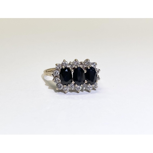 80 - A STRIKING THREE STONE SAPPHIRE CLUSTER RING, with three oval cut sapphires surrounded by eighteen r... 