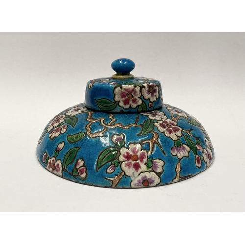 82 - AN EARLY 20TH CENTURY FRENCH POTTERY INKWELL, with cherry blossom design to circular body and cover ... 