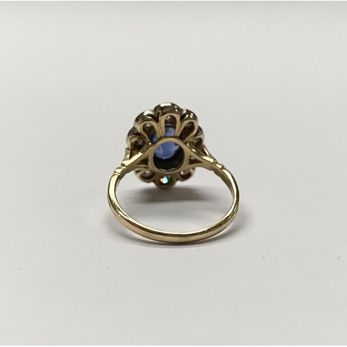 84 - A BEAUTIFUL 18CT YELLOW GOLD SAPPHIRE AND DIAMOND CLUSTER RING, vibrant oval cut bezel set sapphire ... 