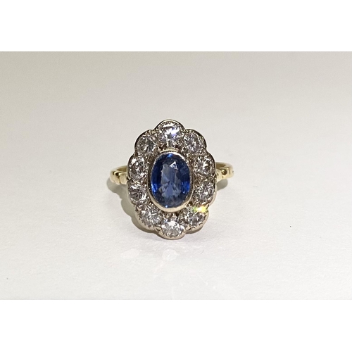 84 - A BEAUTIFUL 18CT YELLOW GOLD SAPPHIRE AND DIAMOND CLUSTER RING, vibrant oval cut bezel set sapphire ... 