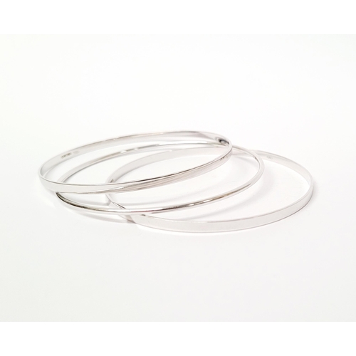 94 - A STUNNING TRIO OF 18CT WHITE GOLD BANGLE BRACLETS, each hallmarked; 18ct white gold. 750. 6cm wide.