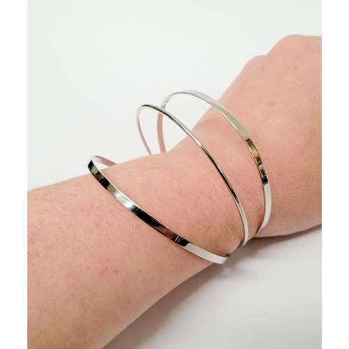 94 - A STUNNING TRIO OF 18CT WHITE GOLD BANGLE BRACLETS, each hallmarked; 18ct white gold. 750. 6cm wide.