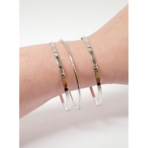 94 - A STUNNING TRIO OF 18CT WHITE GOLD BANGLE BRACLETS, each hallmarked; 18ct white gold. 750. 6cm wide.