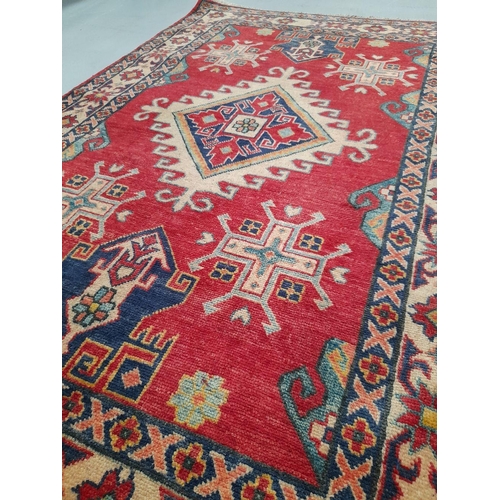 129 - A VIBRANT AFGHAN KAZAK RUG, hand knotted, with central diamond medallion surrounded by geometric des... 