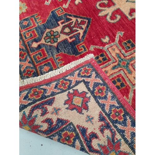 129 - A VIBRANT AFGHAN KAZAK RUG, hand knotted, with central diamond medallion surrounded by geometric des... 