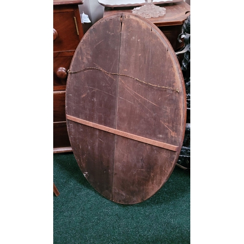 187 - A MAHOGANY INALID OVAL SHAPED BEVELLED WALL MIRROR, very heavy with a panelled wooden back. Frame ha... 