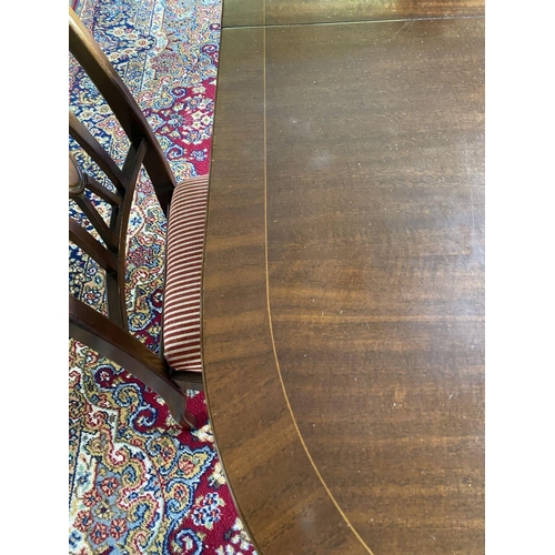 44 - A GOOD MAHOGANY CROSSBANDED EXTENDING DINING TABLE, the oval top with crossbanded border atop turned... 