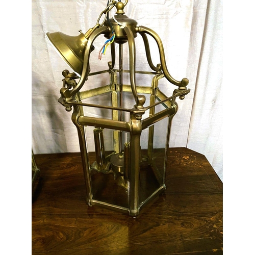 93 - A VERY GOOD QUALITY PAIR OF BRASS GLAZED HANGING LANTERN LIGHTS, each with scrolling open work to th... 