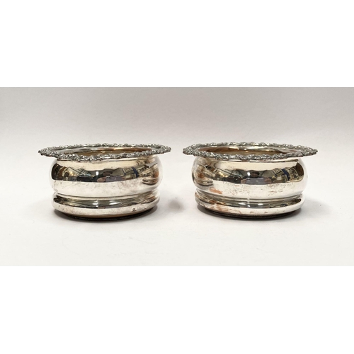 101 - A PAIR OF SMALL VINTAGE SILVER PLATED WINE COASTERS, with decorative floral scrolling borders, hardw... 