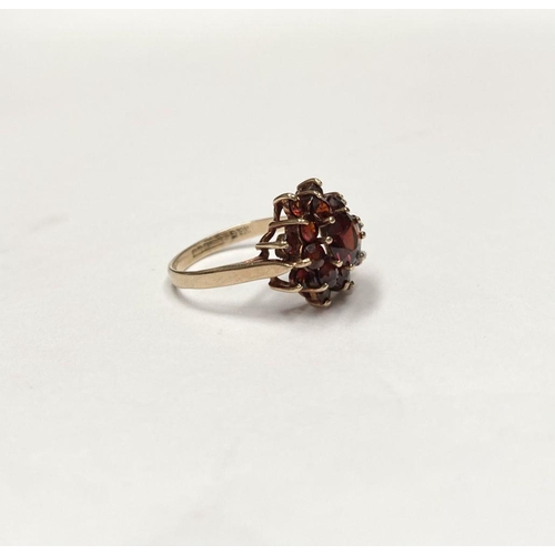 114 - A VINTAGE 9CT GOLD GARNET CLUSTER RING, with central round cut garnet in eight claw setting surround... 