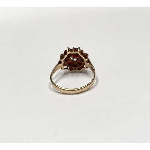 114 - A VINTAGE 9CT GOLD GARNET CLUSTER RING, with central round cut garnet in eight claw setting surround... 