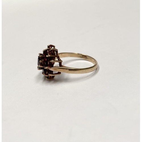 114 - A VINTAGE 9CT GOLD GARNET CLUSTER RING, with central round cut garnet in eight claw setting surround... 