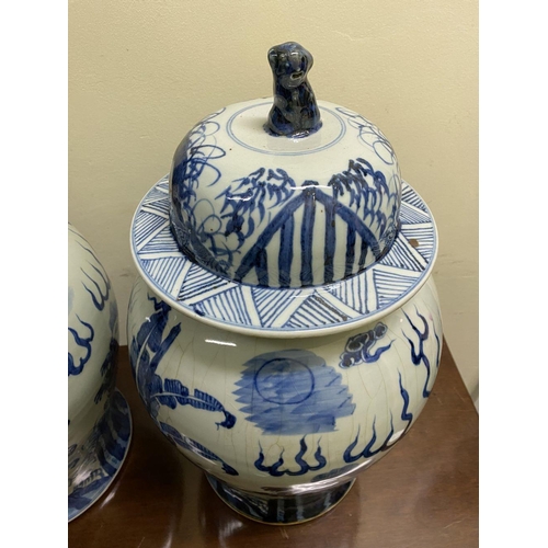 13 - A PAIR OF CHINESE PORCELAIN BLUE AND WHITE TEMPLE VASES, c. late Qing period, with domed cover with ... 