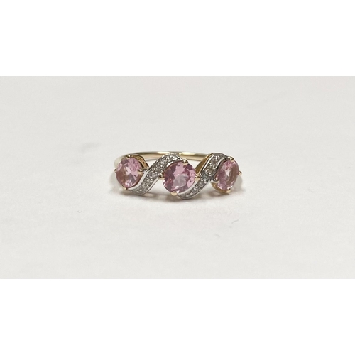 16 - A BEAUTIFUL 9CT GOLD PINK THREE STONE RING, with three pink round cut gemstones in four prong raised... 