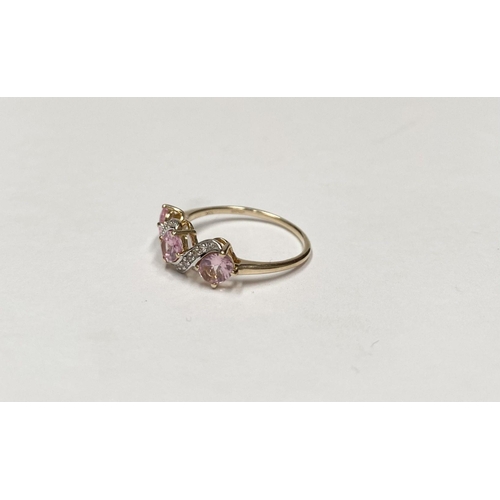 16 - A BEAUTIFUL 9CT GOLD PINK THREE STONE RING, with three pink round cut gemstones in four prong raised... 