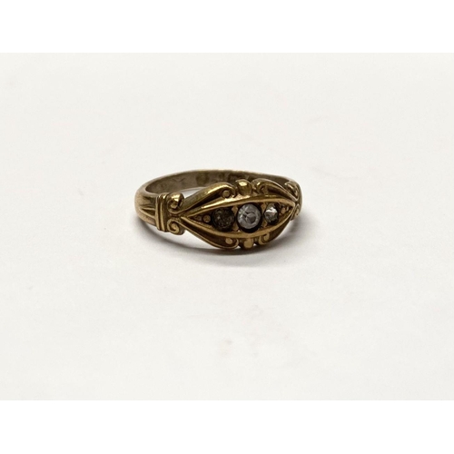 177 - A DECORATIVE THREE STONE DRESS RING, with central round cut clear gemstone flanked by further clear ... 