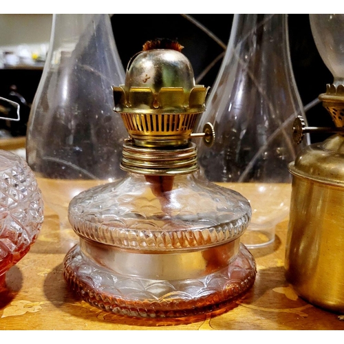 215 - A COLLECTION OF ANTIQUE GLASS & BRASS OIL LAMPS, along with spare clear glass chimneys.