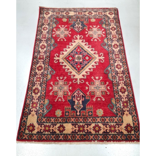 38 - A VIBRANT AFGHAN KAZAK RUG, hand knotted, with central diamond medallion surrounded by geometric des... 