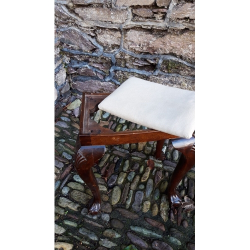 126 - A VINTAGE UPHOLSTERED FOOTSTOOL, with carved scallop shell decoration to the knees, rests on claw on... 