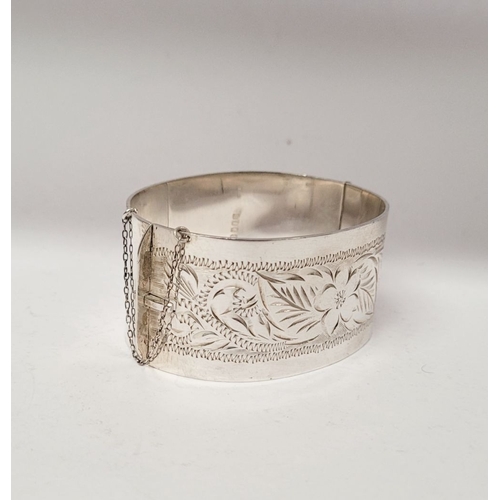 143 - A VERY GOOD QUALITY IRISH SILVER BANGLE, decorated with floral engraved design to one side of exteri... 