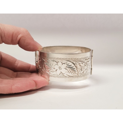 143 - A VERY GOOD QUALITY IRISH SILVER BANGLE, decorated with floral engraved design to one side of exteri... 