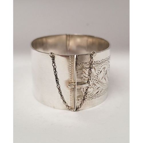 143 - A VERY GOOD QUALITY IRISH SILVER BANGLE, decorated with floral engraved design to one side of exteri... 