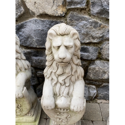 148 - A LARGE PAIR OF STONE GARDEN ORNAMENTS, in the form of lions above armorial plaque, on square steppe... 