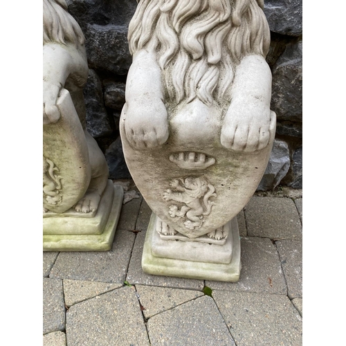 148 - A LARGE PAIR OF STONE GARDEN ORNAMENTS, in the form of lions above armorial plaque, on square steppe... 