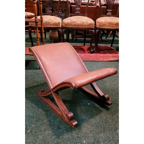 258 - AN ANTIQUE STYLE LEATHER TOPPED X-FRAMED ROCKING STOOL, with carved scroll detail to the frame & fin... 