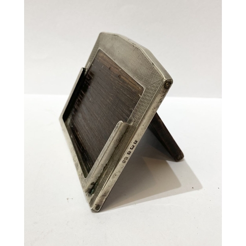 285 - A MINIATURE SILVER PHOTO FRAME, the silver shaped frame with engine turned pattern to front, hardwoo... 