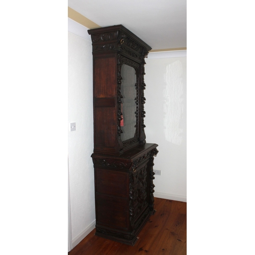 321 - A HIGHLY CARVED GOTHIC REVIVAL BOOKCASE, with glass door revealing shelved interior, above base with... 