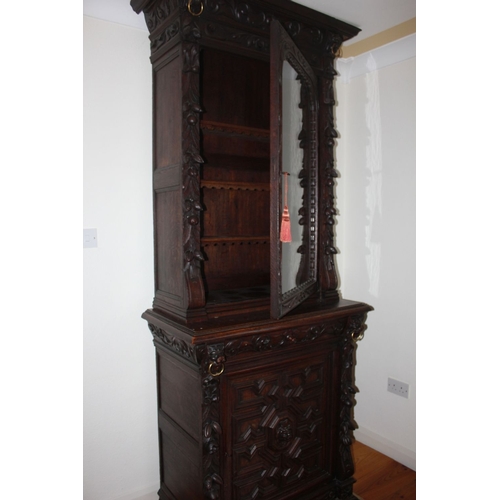 321 - A HIGHLY CARVED GOTHIC REVIVAL BOOKCASE, with glass door revealing shelved interior, above base with... 