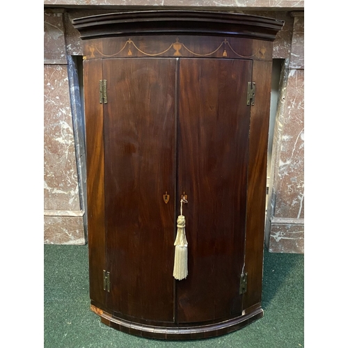 52 - A GEORGIAN BOW FRONTED HANGING CORNER CABINET, with a graduated pediment top, over a row of inlaid u... 