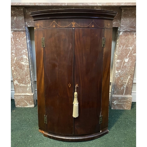 52 - A GEORGIAN BOW FRONTED HANGING CORNER CABINET, with a graduated pediment top, over a row of inlaid u... 