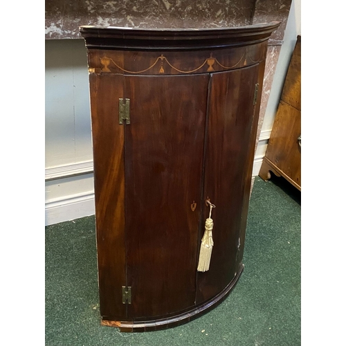 52 - A GEORGIAN BOW FRONTED HANGING CORNER CABINET, with a graduated pediment top, over a row of inlaid u... 