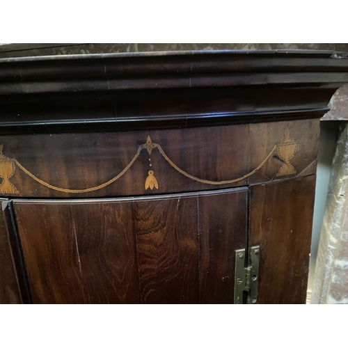 52 - A GEORGIAN BOW FRONTED HANGING CORNER CABINET, with a graduated pediment top, over a row of inlaid u... 