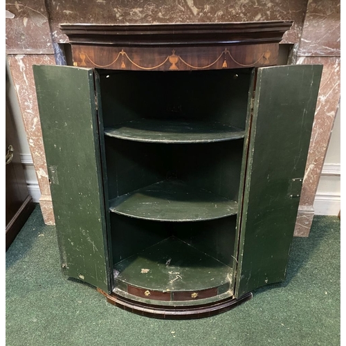 52 - A GEORGIAN BOW FRONTED HANGING CORNER CABINET, with a graduated pediment top, over a row of inlaid u... 