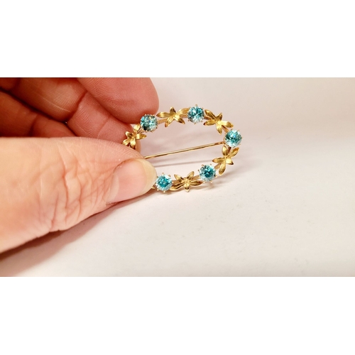 6 - A CASED 9CT YELLOW GOLD & TOPAZ BLUE GEMSTONE SET BROOCH, the brooch decorated with floral design an... 