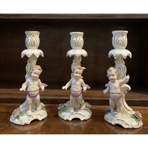 78 - THREE EARLY 20TH CENTURY GERMAN PORCELAIN CHERUB CANDLESTICKS, marked to base with blue mark featuri... 