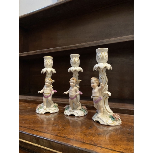 78 - THREE EARLY 20TH CENTURY GERMAN PORCELAIN CHERUB CANDLESTICKS, marked to base with blue mark featuri... 