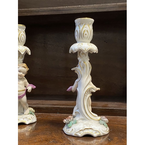 78 - THREE EARLY 20TH CENTURY GERMAN PORCELAIN CHERUB CANDLESTICKS, marked to base with blue mark featuri... 