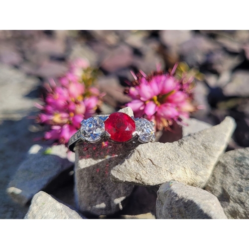 11 - A PRETTY THREE STONE DIAMOND & RUBY RING, the central ruby stone 1.65cts, flanked by a round cut dia... 