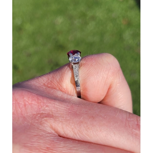 11 - A PRETTY THREE STONE DIAMOND & RUBY RING, the central ruby stone 1.65cts, flanked by a round cut dia... 