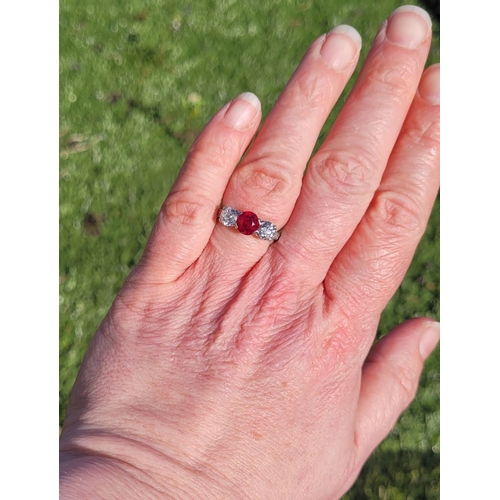 11 - A PRETTY THREE STONE DIAMOND & RUBY RING, the central ruby stone 1.65cts, flanked by a round cut dia... 