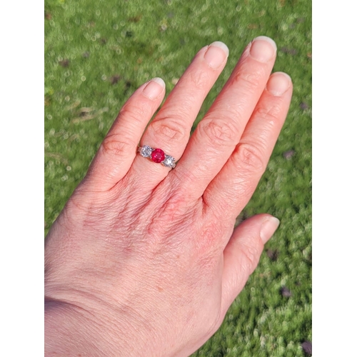 11 - A PRETTY THREE STONE DIAMOND & RUBY RING, the central ruby stone 1.65cts, flanked by a round cut dia... 