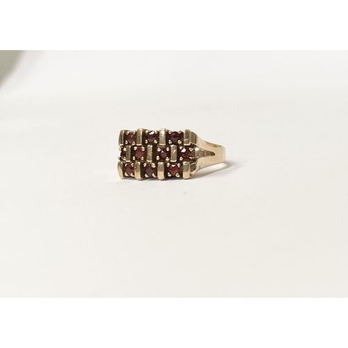 150 - A 9CT YELLOW GOLD THREE ROW GARNET COCKTAIL RING, featuring striking design with three rows of round... 